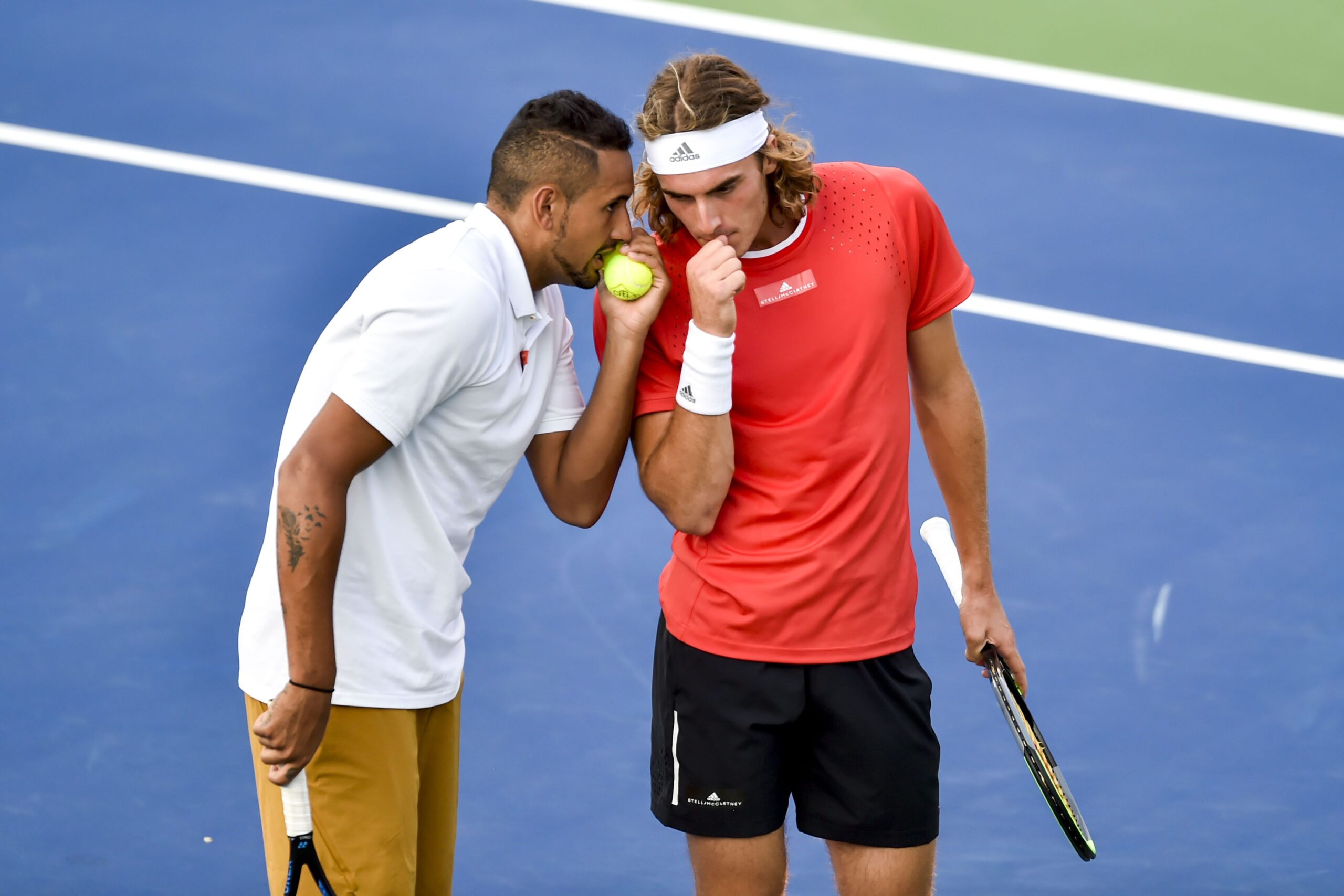 Two tennis players share a private moment on the court during a match.