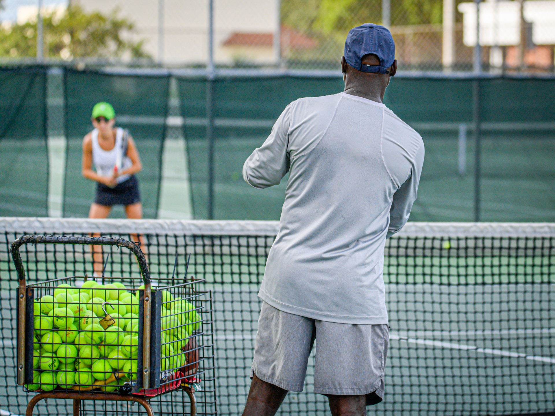 A tennis coach instructs a player during practice on a court.