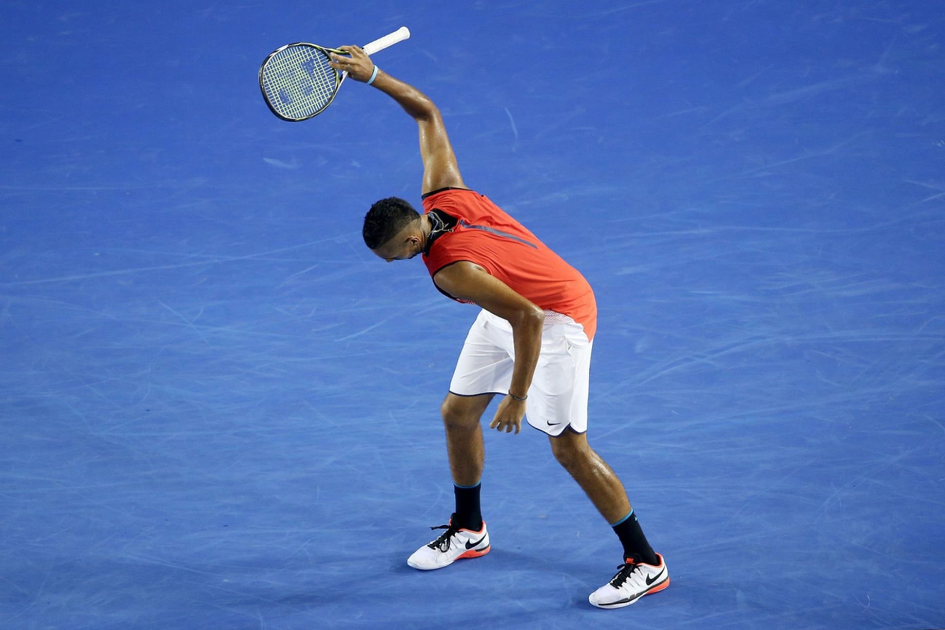 Tennis player preparing to serve during a match on a blue court.