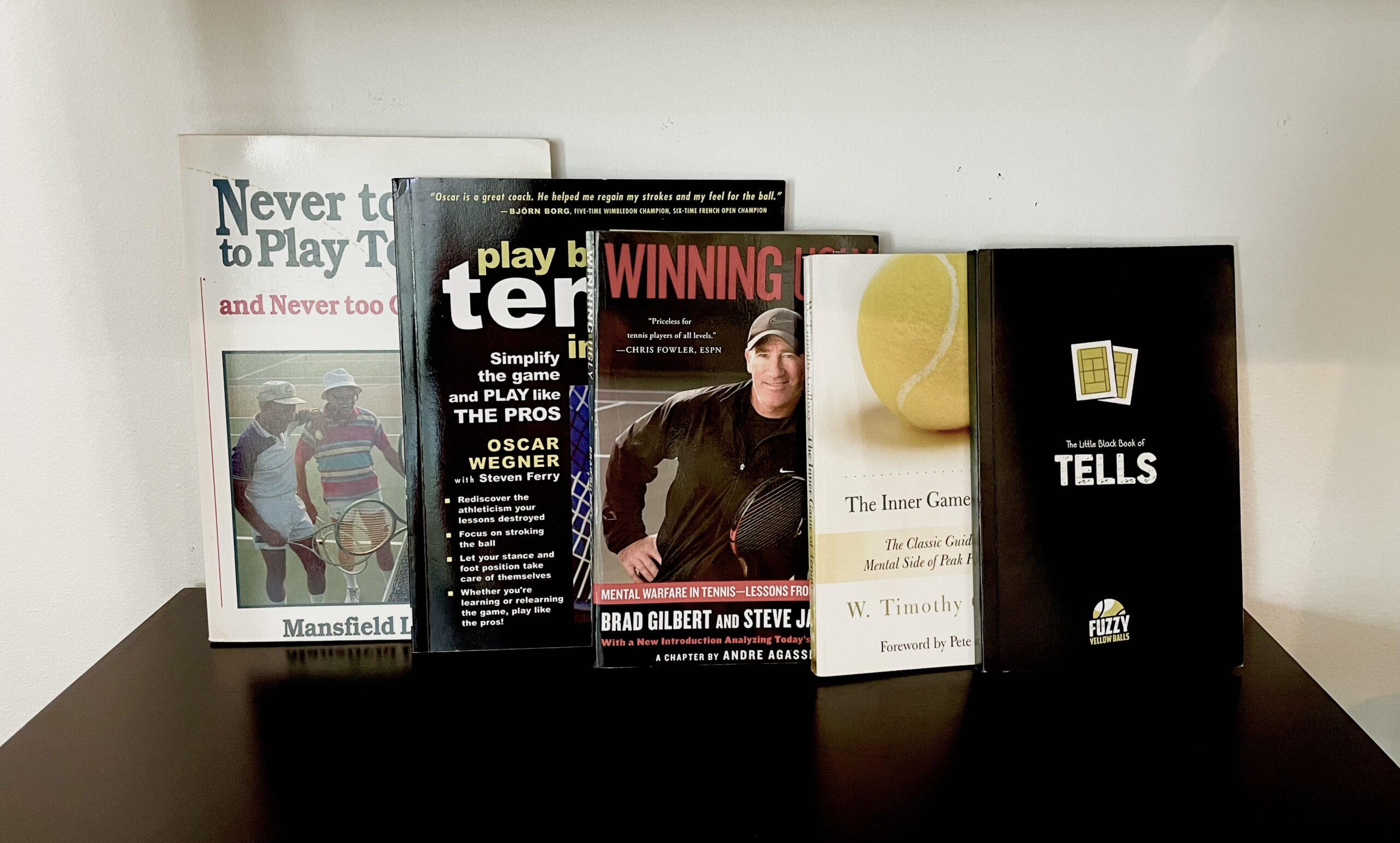 A row of various books and media items on a white shelf.