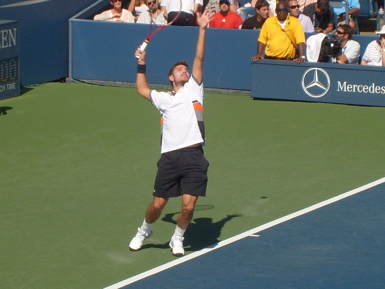 Male tennis player serving on a blue court during a match.