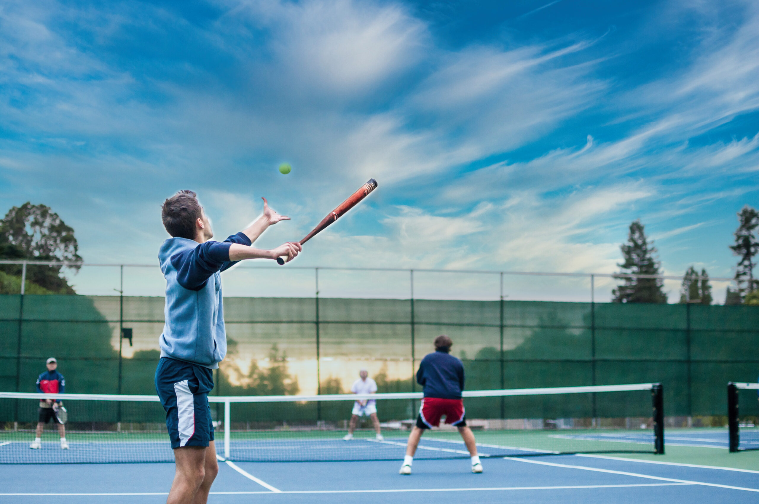 Two men playing tennis on an outdoor court under a blue sky.