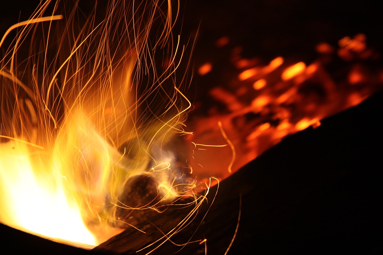 Close-up of intense flames with sparks flying in the dark.