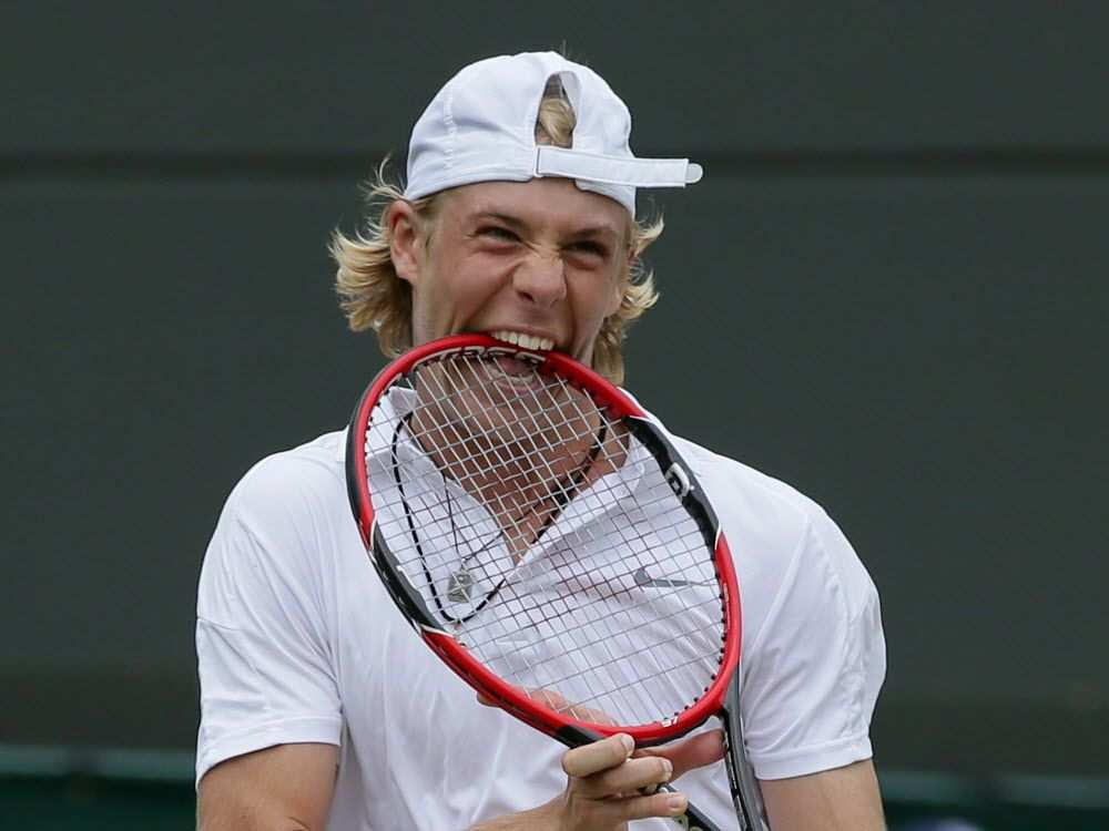 Photo of tennis player biting his racket.